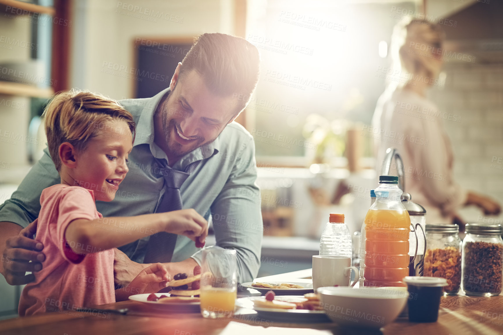 Buy stock photo Shot of a man sitting with his son while he's having breakfast