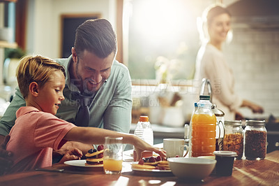 Buy stock photo Shot of a man sitting with his son while he's having breakfast