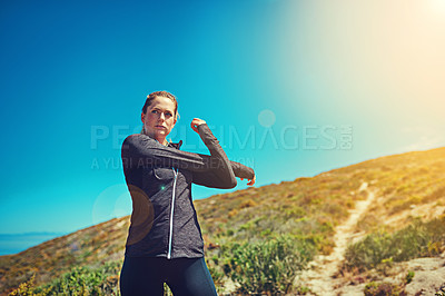 Buy stock photo Shot of a sporty young woman stretching before her workout outdoors