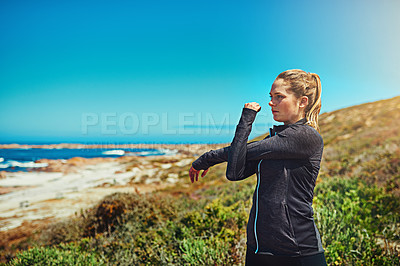 Buy stock photo Shot of a sporty young woman stretching before her workout outdoors