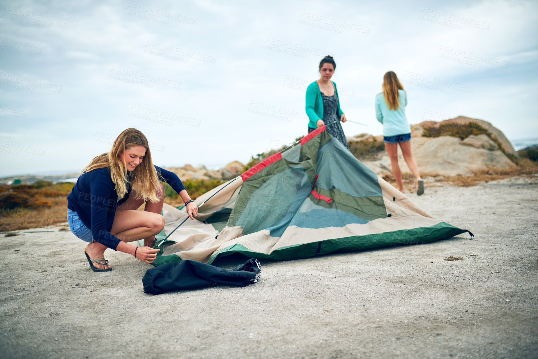 Buy stock photo Shot of a group of female friends setting up a tent outdoors