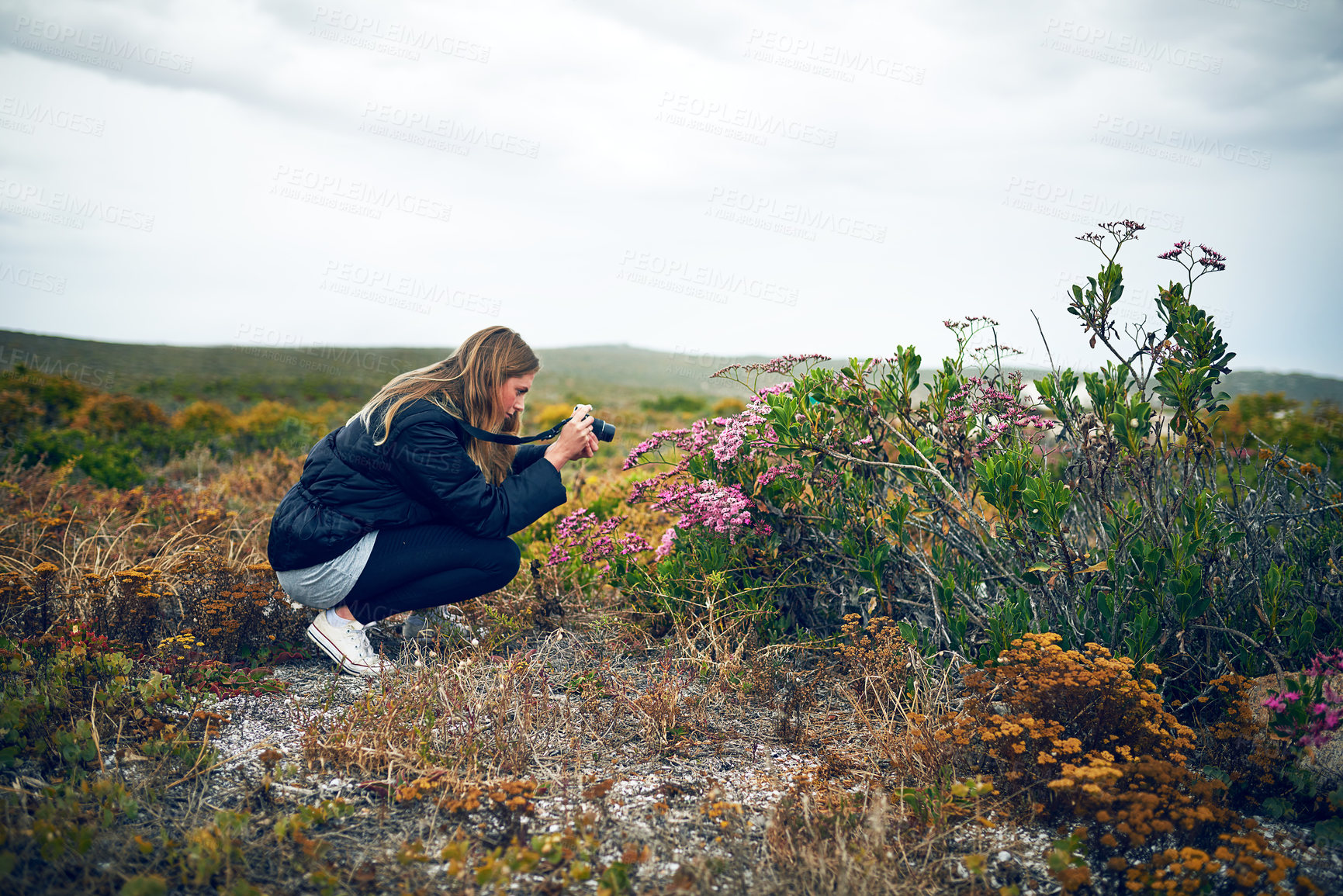 Buy stock photo Shot of a young woman taking a photograph with her camera outdoors