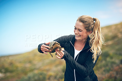 Buy stock photo Shot of a young woman holding a tortoise outdoors