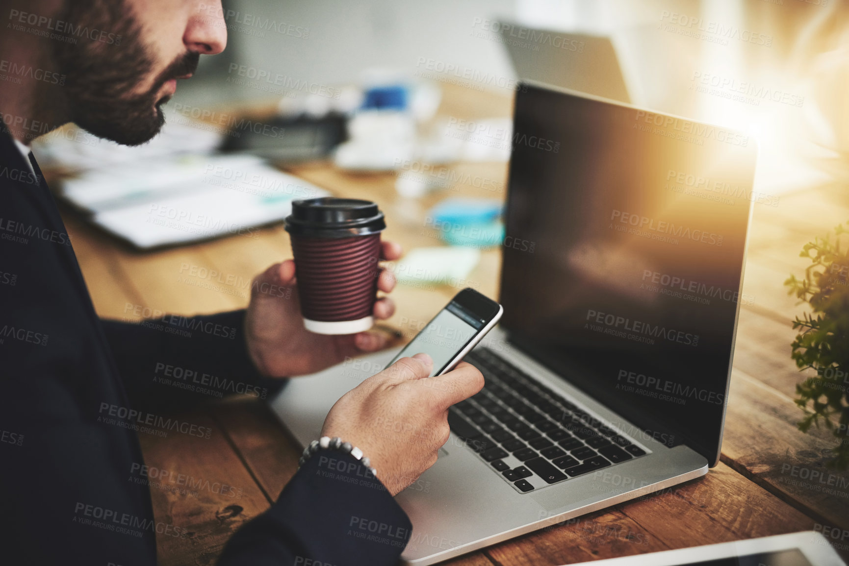 Buy stock photo Cropped shot of a businessman using a mobile phone and laptop at his work desk