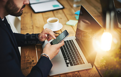 Buy stock photo Cropped shot of a businessman using a mobile phone and laptop at his work desk