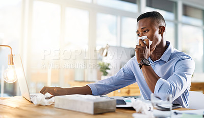 Buy stock photo Shot of a young businessman making use of tissues for his cold while trying to work in the office