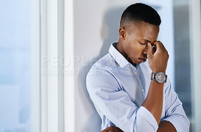 Buy stock photo Shot of a young and stressed businessman suffering from a headache while trying to work in the office