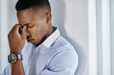Buy stock photo Shot of a young and stressed businessman suffering from a headache while trying to work in the office