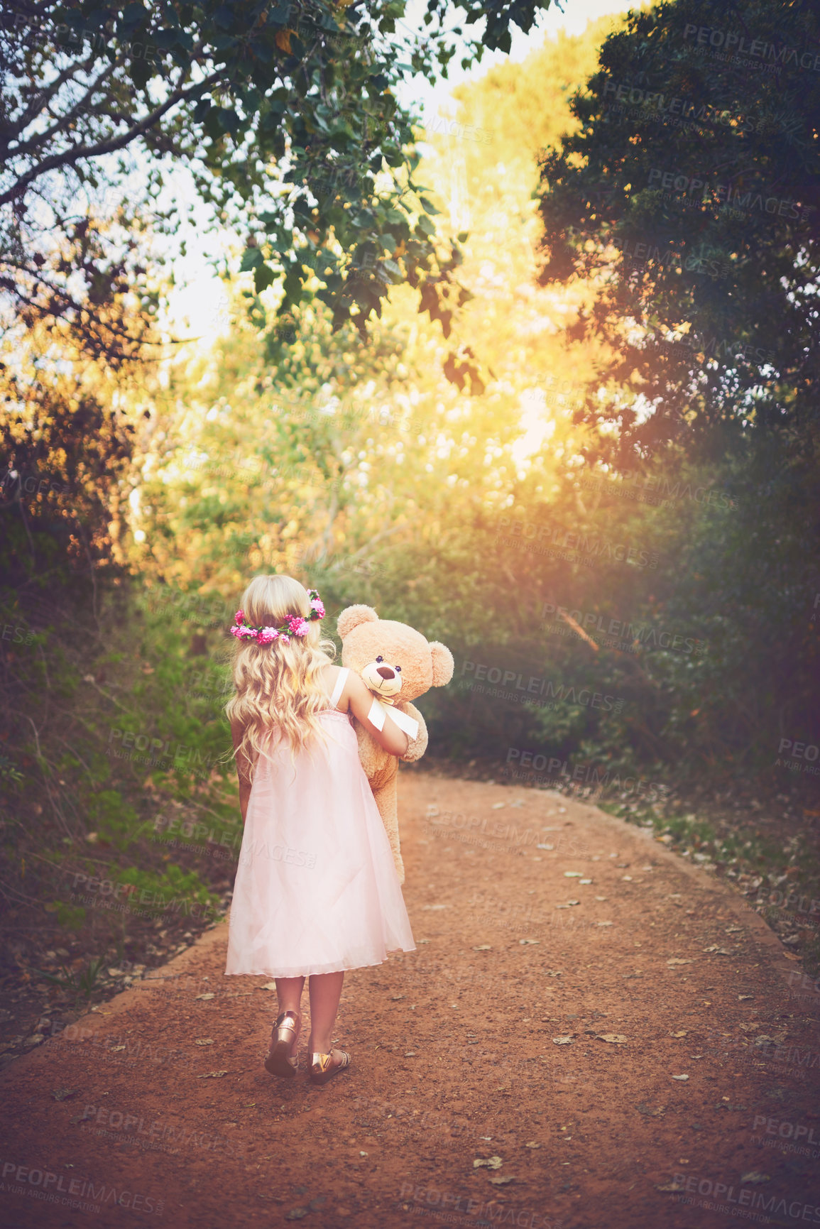 Buy stock photo Shot of a unrecognizable little girl walking with her teddy bear in the middle of a dirt road