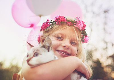 Buy stock photo Shot of a happy little girl holding a kitten and looking at the camera outside in the nature