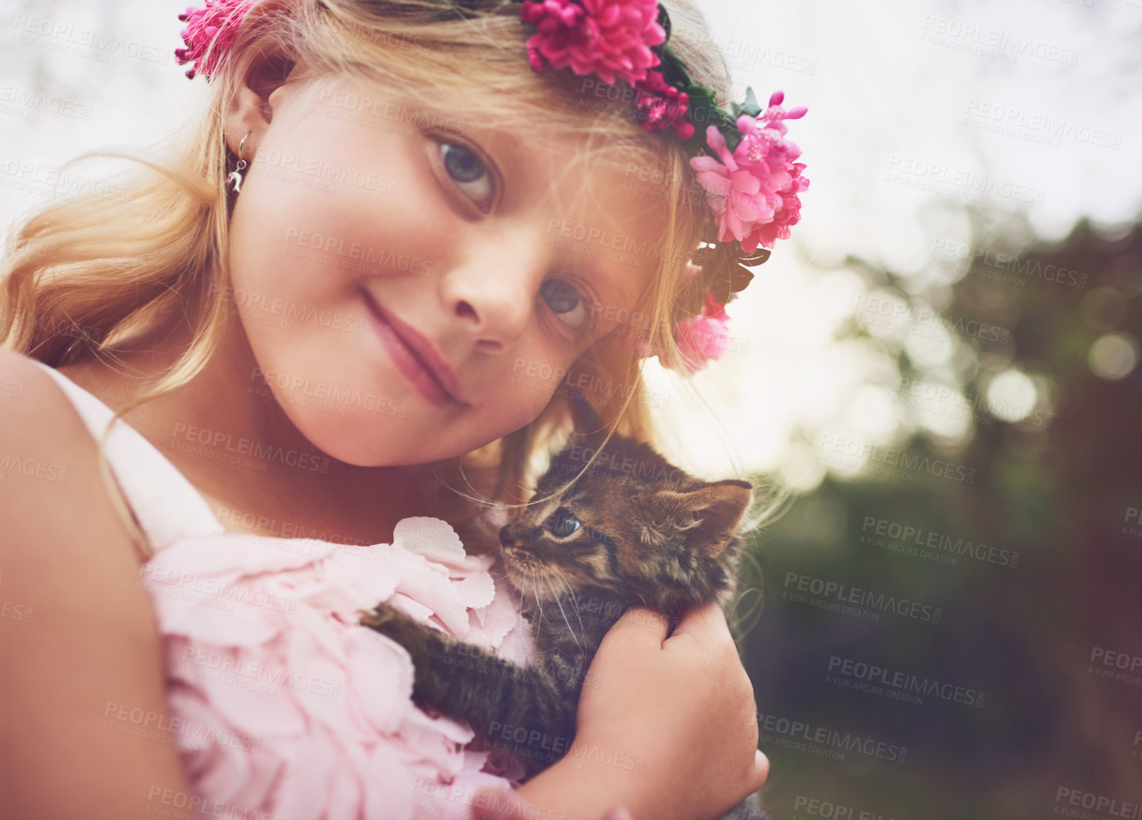 Buy stock photo Shot of a happy little girl holding a kitten and looking at the camera outside in the nature