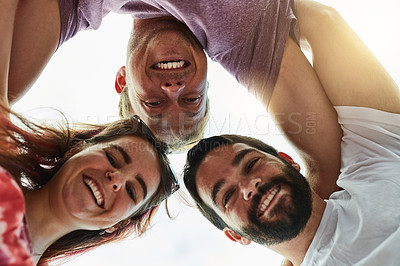 Buy stock photo Low angle shot of a group of young friends looking down and smiling at the camera while standing outside