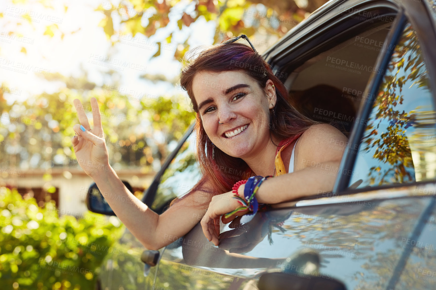Buy stock photo Shot of a young woman showing a peace sign and looking at the camera while sitting in the backseat of a car