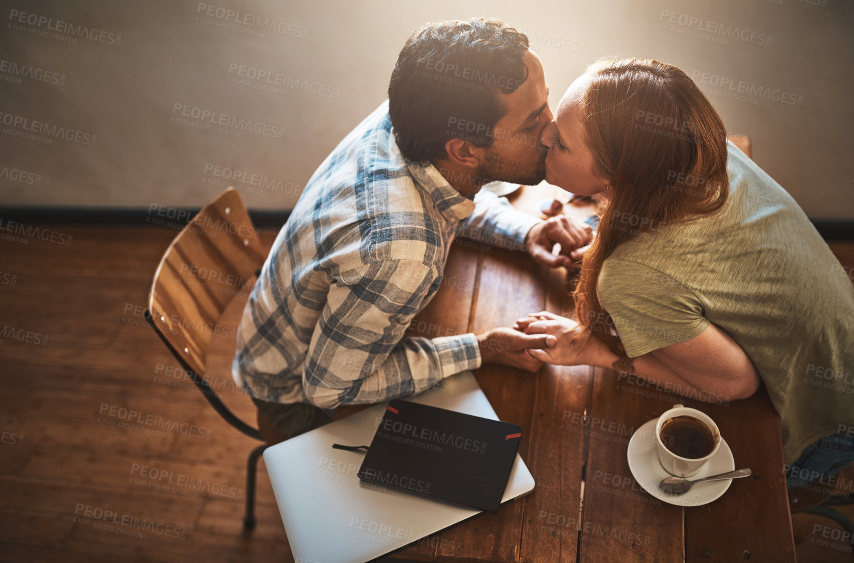 Buy stock photo Cafe, kiss and couple on a coffee shop date together holding hands with love and care. Morning, restaurant above and happy young people with tea dating with happiness at a table with a hot drink