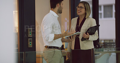 Buy stock photo Cropped shot of two businesspeople looking over a tablet while standing in the office lobby