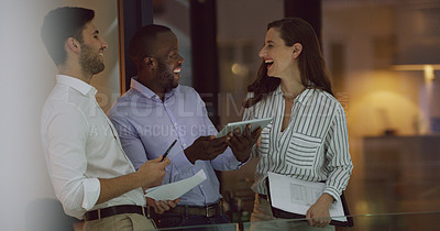 Buy stock photo Cropped shot of three businesspeople looking over a tablet while standing in the office lobby