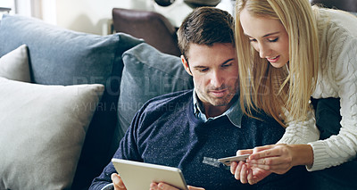 Buy stock photo Cropped shot of an affectionate young couple using their digital tablet to do some online shopping at home