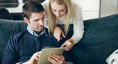 Buy stock photo Cropped shot of an affectionate young couple using their digital tablet to do some online shopping at home
