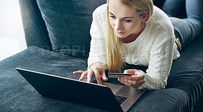 Buy stock photo Cropped shot of an attractive young woman using her laptop to do some online shopping at home
