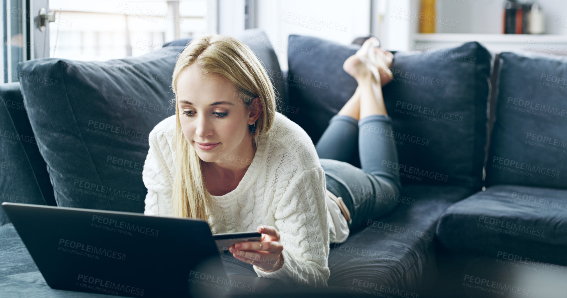 Buy stock photo Full length shot of an attractive young woman using her laptop to do some online shopping at home