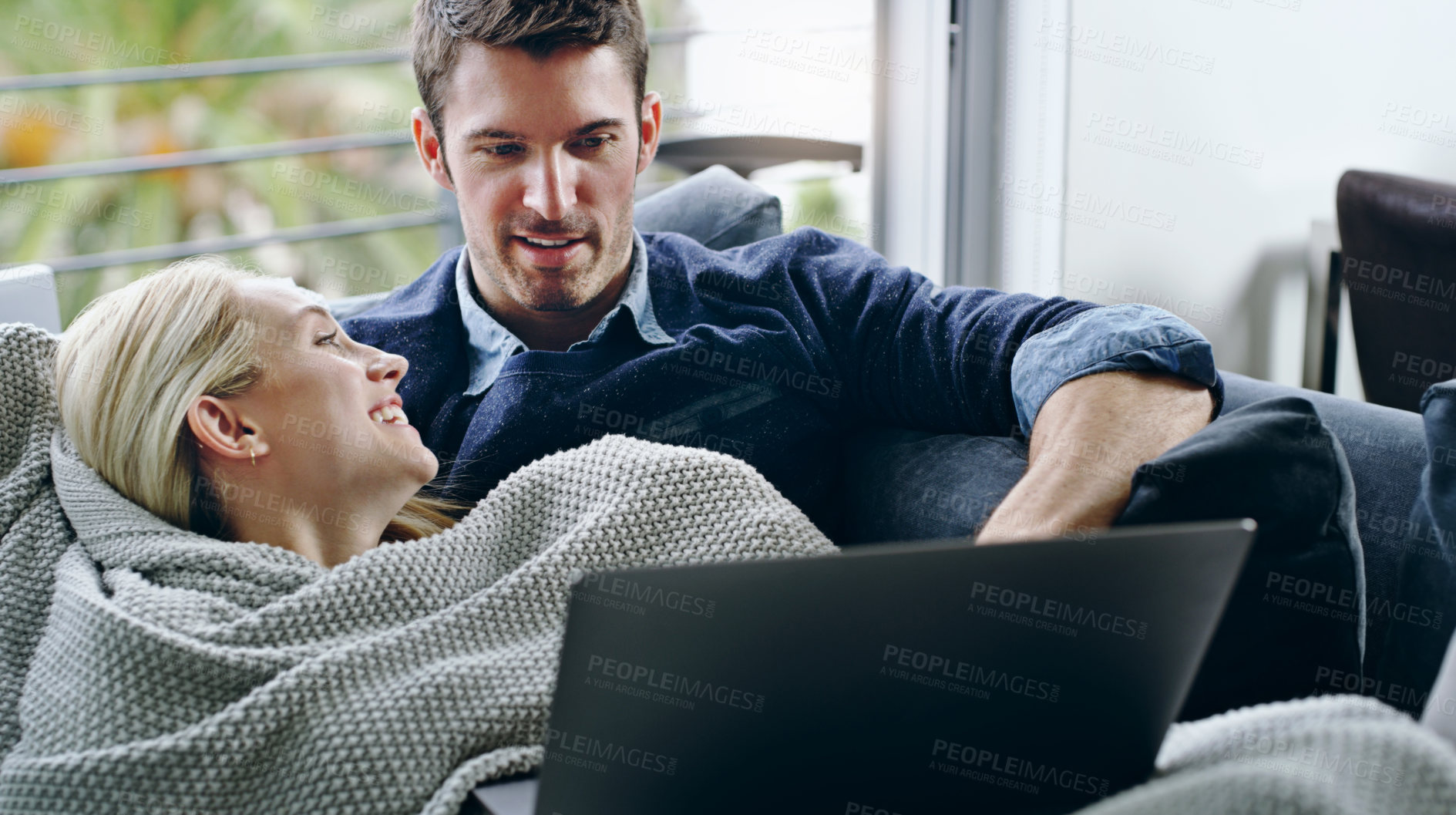 Buy stock photo Cropped shot of an affectionate young couple watching a movie on their laptop while relaxing on the sofa at home