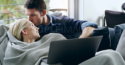 Buy stock photo Cropped shot of a handsome young man kissing his girlfriend on the forehead while lying on their sofa at home