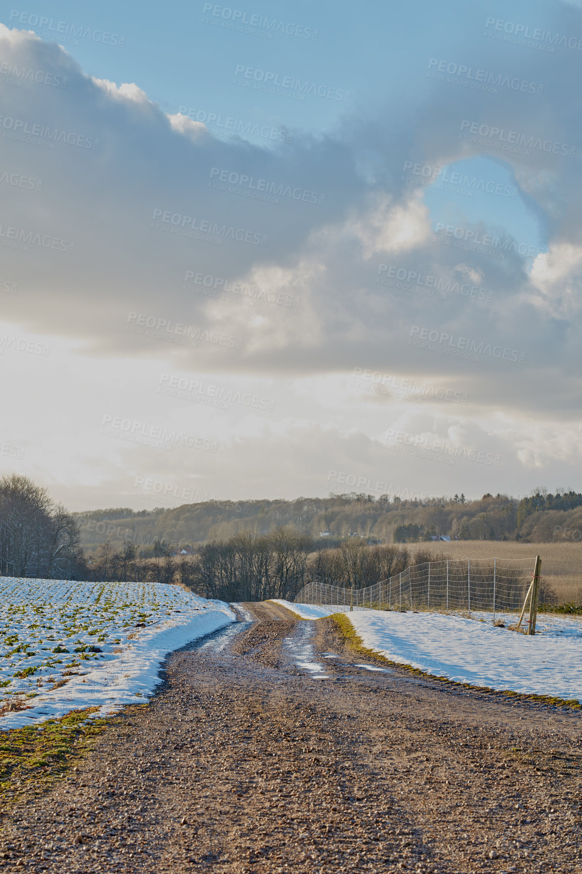 Buy stock photo Dirt road, cloudy sky and fence with snow terrain of natural scenery, season or climate change in countryside. Landscape, nature or farmland with path, trail or winter weather in outdoor wilderness