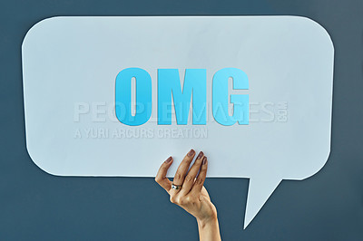 Buy stock photo Cropped studio shot of a woman holding up a speech bubble with a “OMG” on it against a gray background