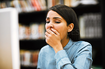 Buy stock photo Shot of a university student yawning while working on a computer in the library at campus
