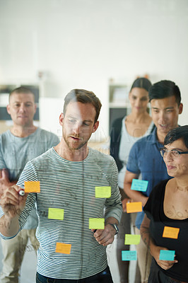 Buy stock photo Cropped shot of a group of young designers planning on a glass board