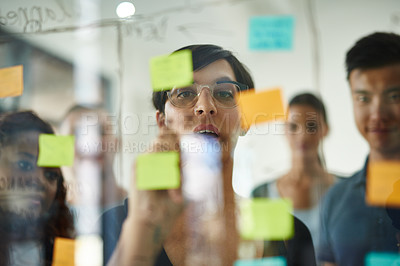 Buy stock photo Cropped shot of a group of young designers planning on a glass board