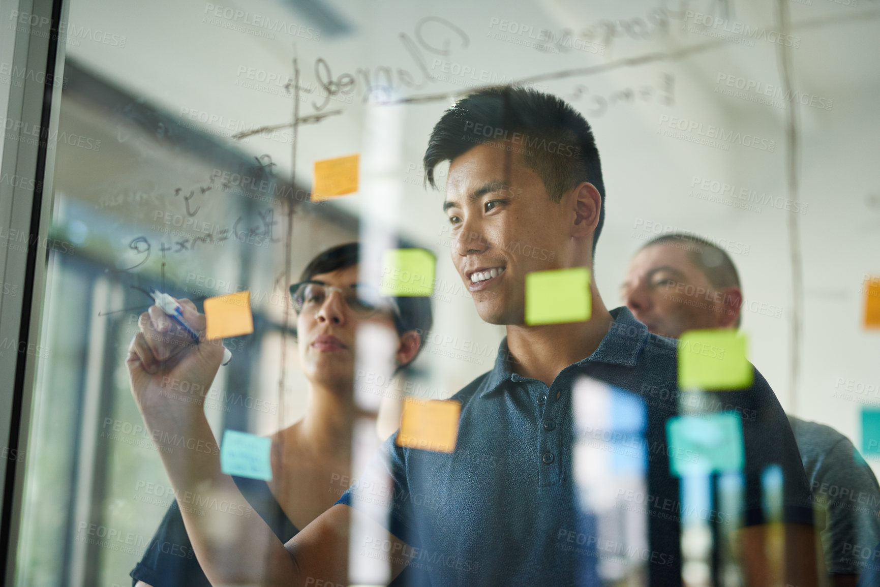 Buy stock photo Cropped shot of a group of young designers planning on a glass board