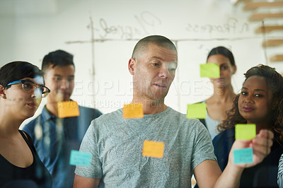 Buy stock photo Teamwork, planning and writing on sticky notes while brainstorming, talking and sharing ideas. Manager leading diverse group of creative business people in meeting while showing vision and innovation