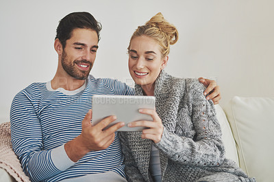 Buy stock photo Shot of a young couple using a digital tablet on their sofa at home