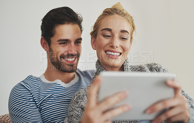 Buy stock photo Shot of a young couple using a digital tablet on their sofa at home