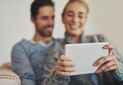 Buy stock photo Shot of a young couple using a digital tablet on their sofa at home