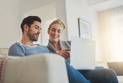Buy stock photo Shot of a young couple using a laptop on their sofa at home