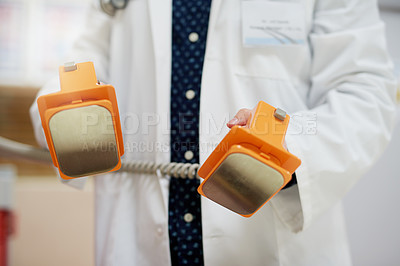 Buy stock photo Shot of an unrecognisable doctor using a defibrillator in a hospital
