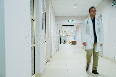 Buy stock photo Shot of a doctor walking in the corridor of a hospital