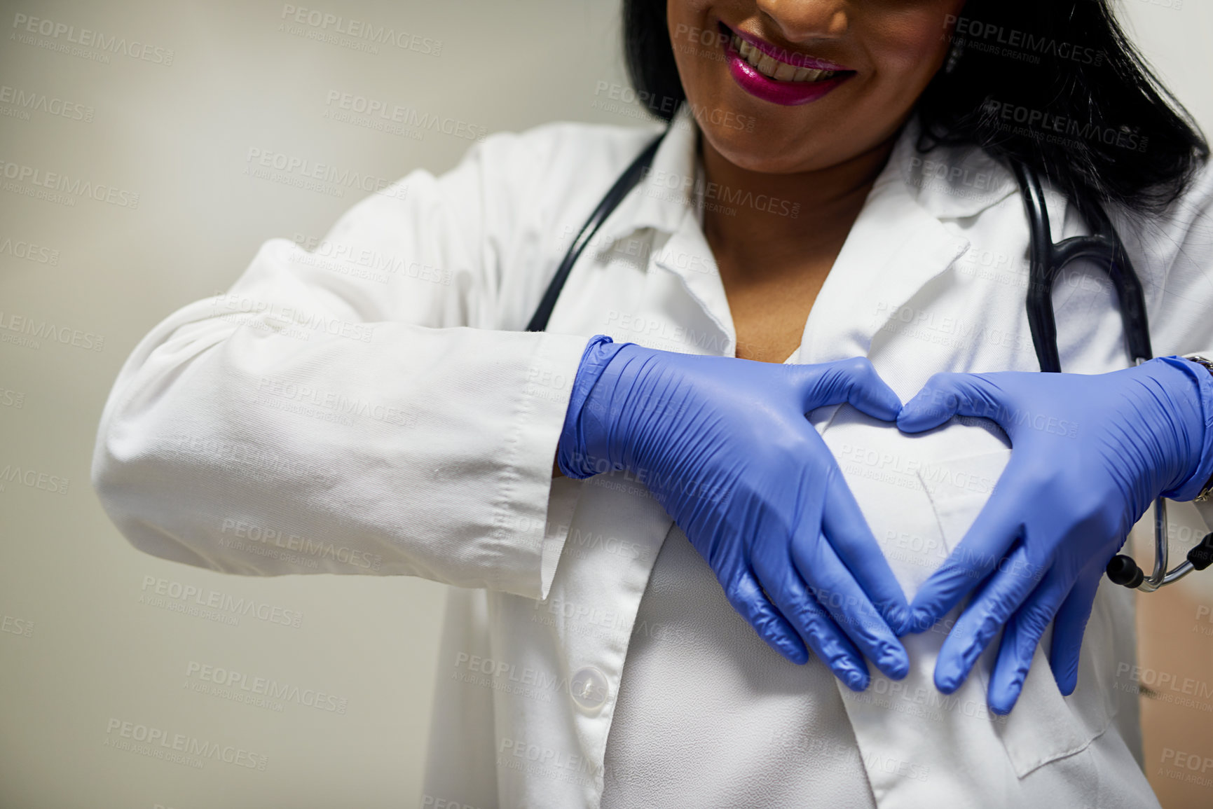 Buy stock photo Shot of an unrecognisable doctor forming a heart shape with her hands against her chest