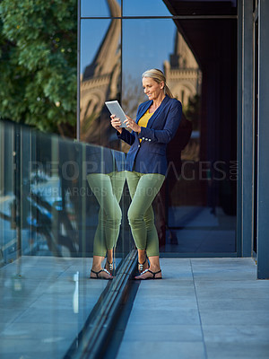 Buy stock photo Shot of a mature businesswoman using a digital tablet outside