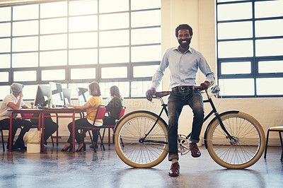Buy stock photo Shot of a handsome man on a bicycle in a modern office