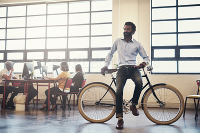 Buy stock photo Shot of a handsome man on a bicycle in a modern office