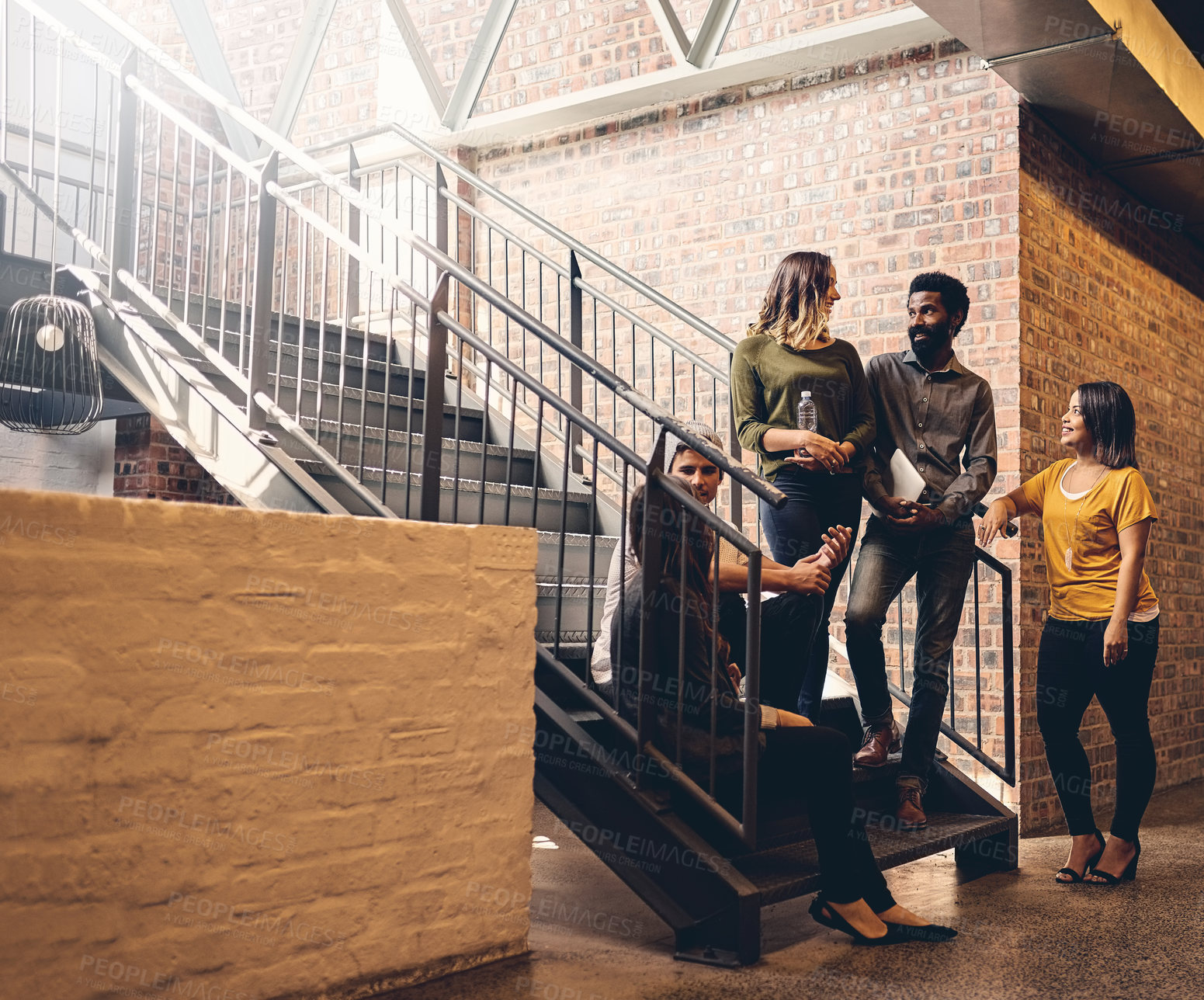 Buy stock photo Full length shot of a group of young designers gathered in a stairwell at the office