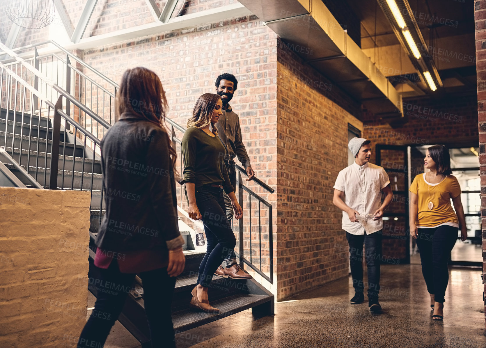 Buy stock photo Full length shot of a group of young designers walking through their office corridors