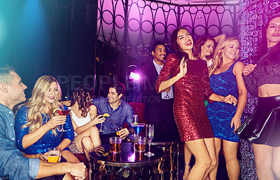 Buy stock photo Shot of a group of young adults enjoying themselves while out in a nightclub