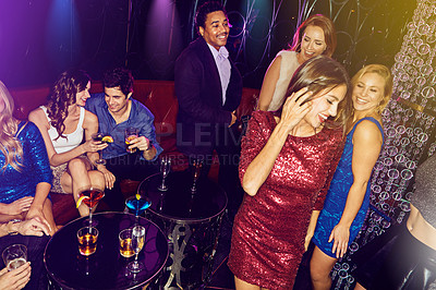 Buy stock photo Shot of a group of young adults enjoying themselves while out in a nightclub