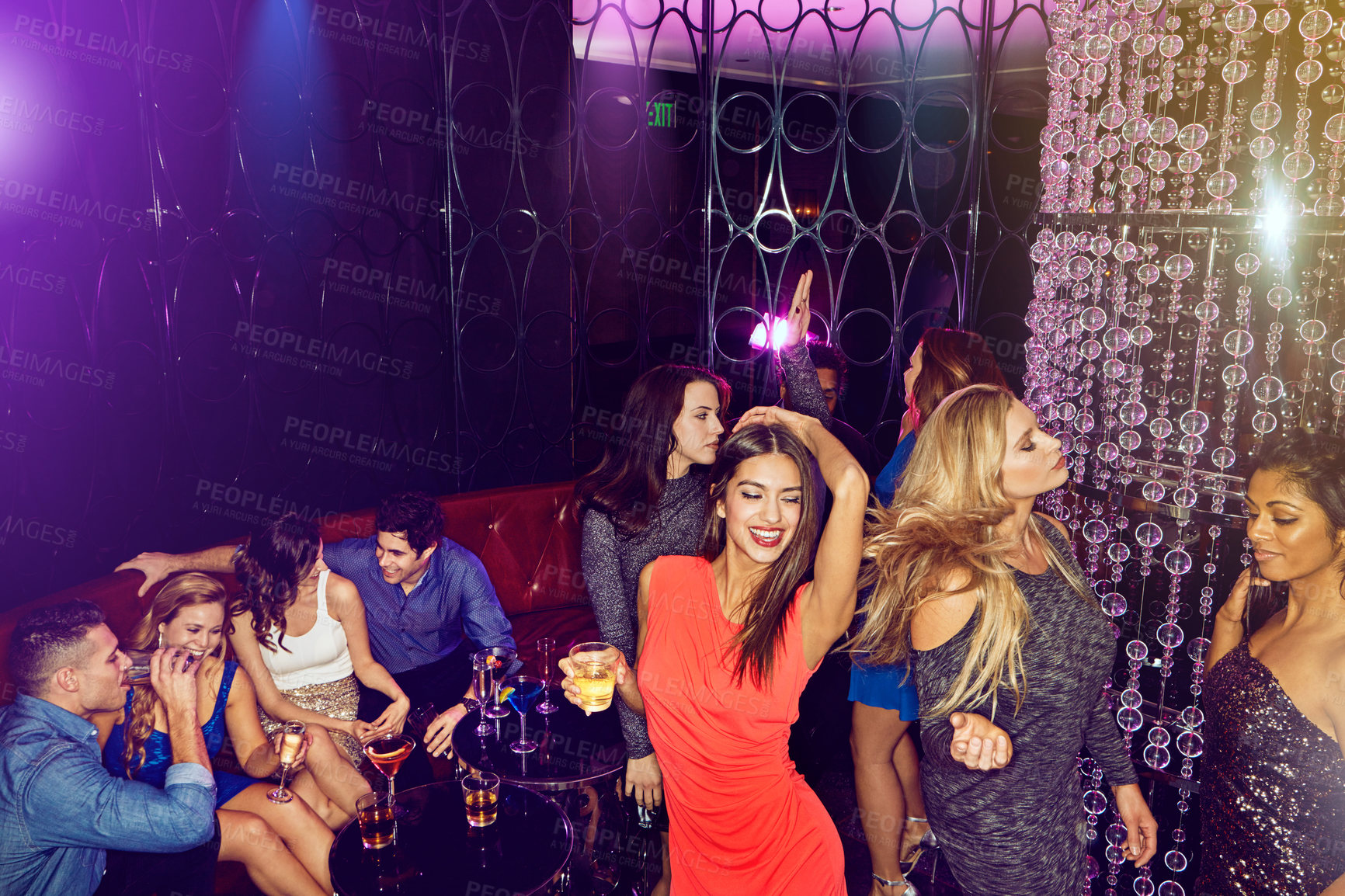 Buy stock photo Shot of a group of young adults enjoying themselves while out in a nightclub