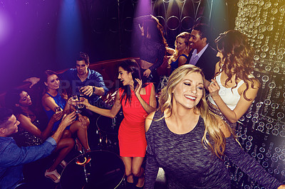 Buy stock photo Shot of a group of young adults enjoying themselves while out in a nightclub