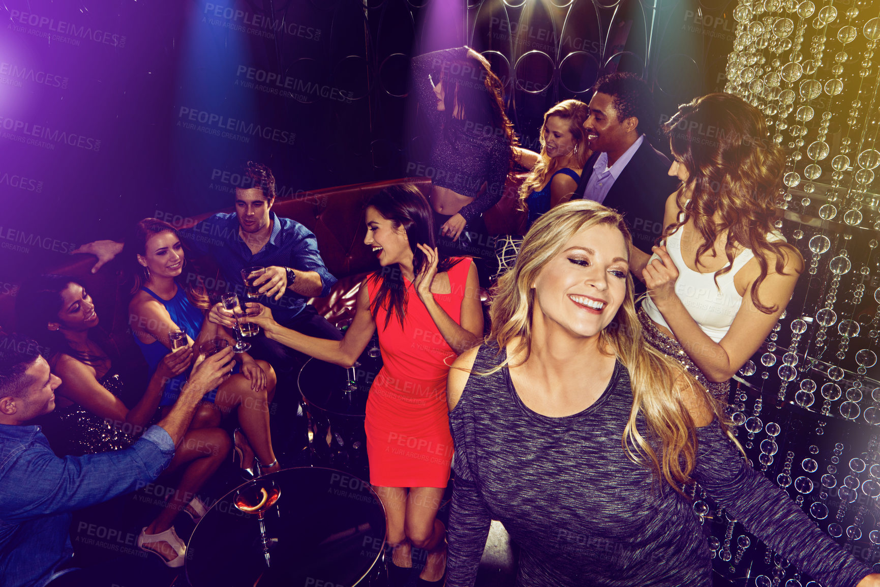 Buy stock photo Shot of a group of young adults enjoying themselves while out in a nightclub